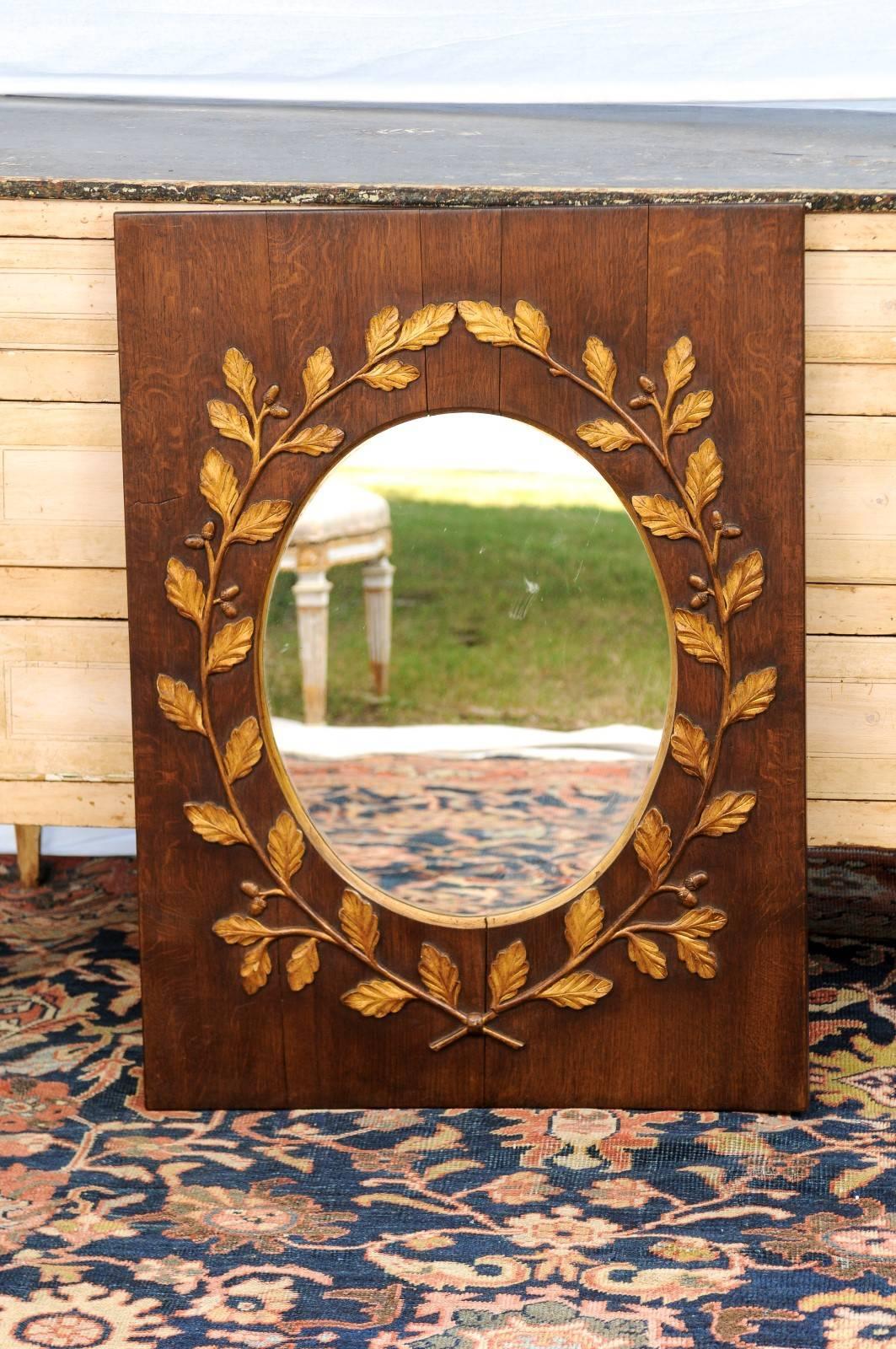 This exquisite English vertical mirror from the late 19th century features a simple rectangular frame with clear oval mirror in its centre. The eye is immediately attracted to the contrast between this simple layout and the exquisite gilded wreath