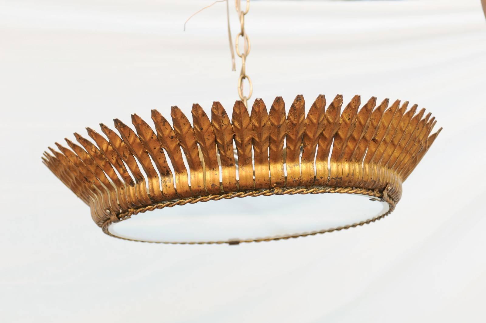 This Spanish mid-20th century crown semi-flush gilt metal light fixture with frosted glass features a single row of leaf motifs over a thin twisted surround. The two lights sit behind a frosted glass bottom that illuminates the room without being