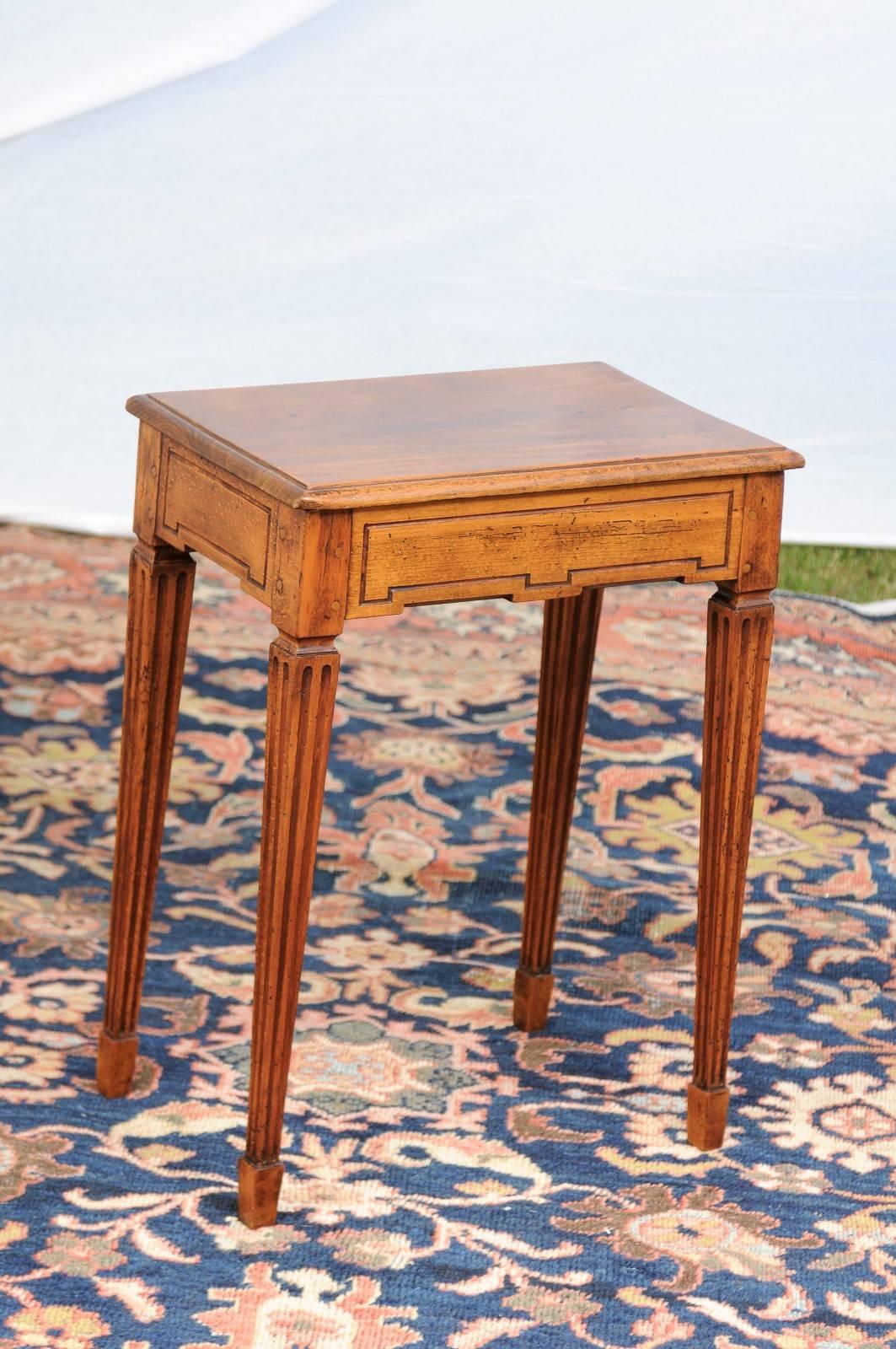 This petite French oak and walnut side table from the late 19th century features a rectangular tilt-top with rounded edge over a geometrically carved apron on all sides. This low relief carving brings a sense of simplicity. The small size table is