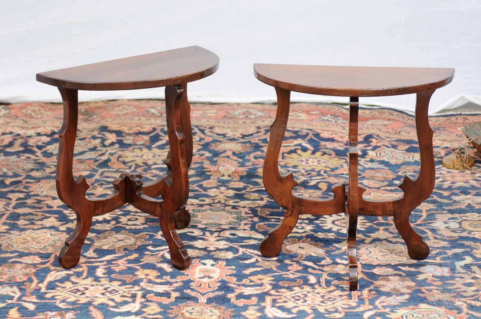This pair of petite Italian Baroque style walnut demilune tables features typical half-moon shaped tops over three dimensional lyre-shaped legs. Each table is made of three carved wooden legs supporting the top, allowing the tables to stand on their