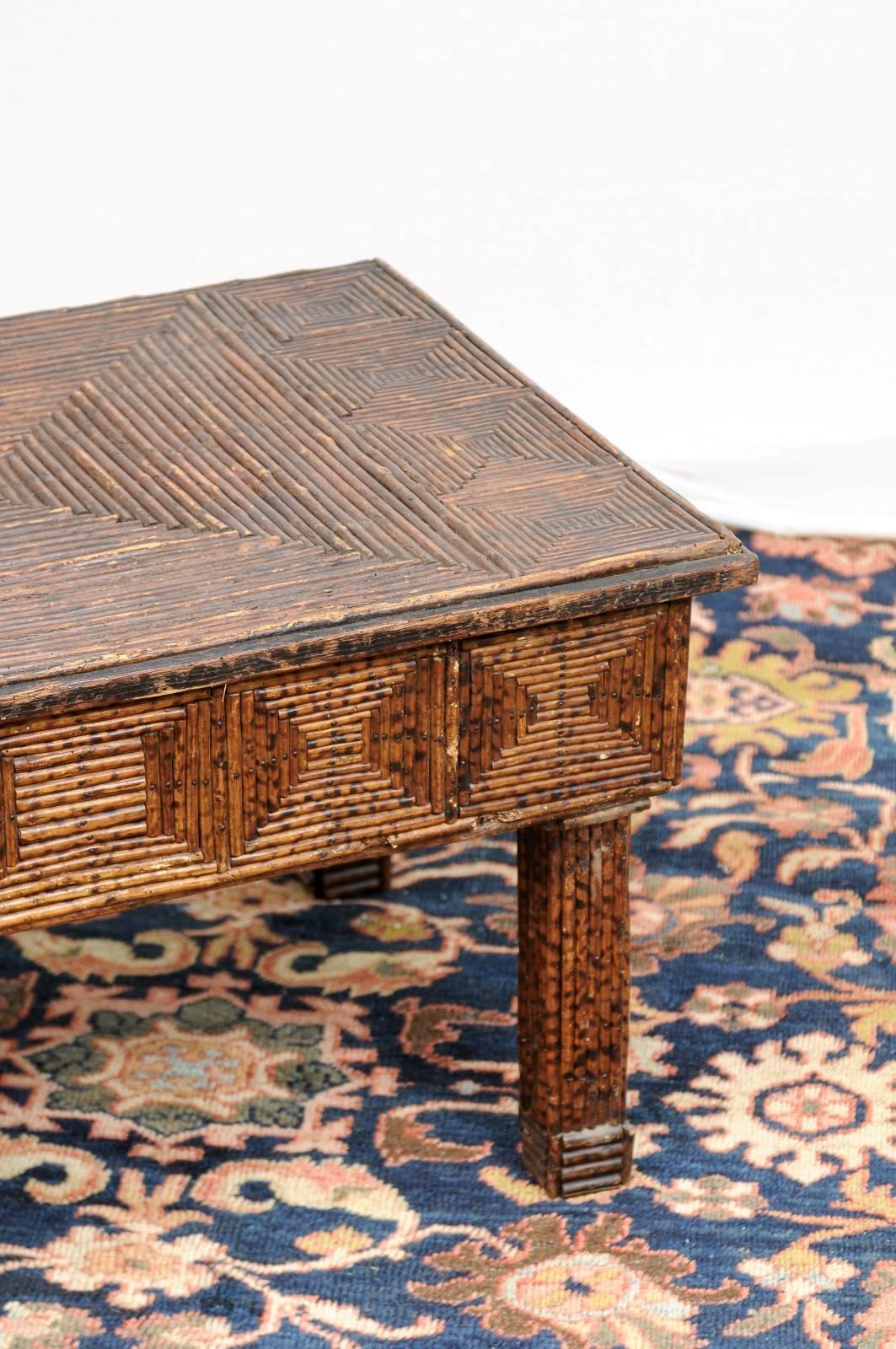 This English coffee table from the late 19th century features a body made of twigs. Its rectangular top is adorned with geometrical motifs, made of triangles in the centre, placed in a way giving the illusion of a pyramid seen from the top. A