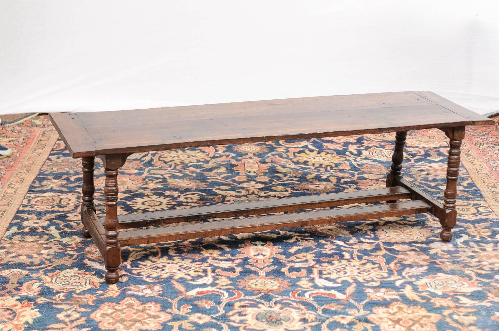 This French long wooden coffee table from the turn of the century (19th-20th century) is made of oak and features a two-plank rectangular top framed on the sides by two smaller pieces. The table, which could also be used as a bench is raised on four