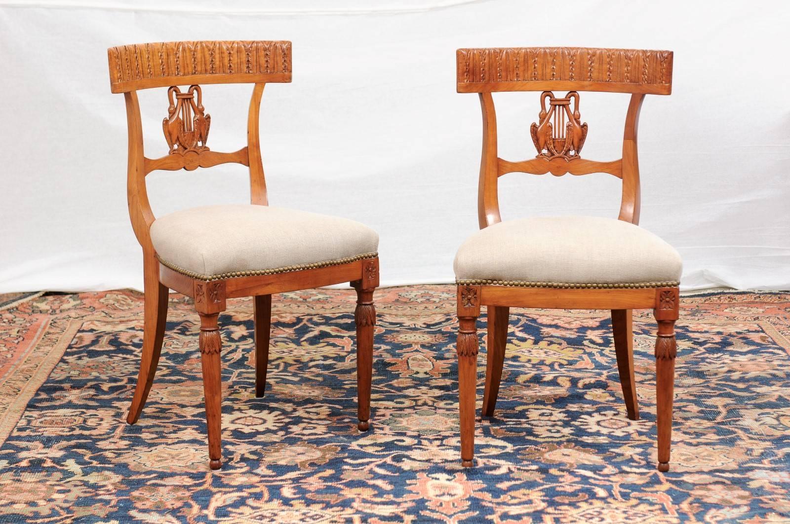 This pair of Italian Neoclassical style walnut side chairs from the mid-19th century features slightly concave pierced backs, marrying perfectly the sitter's body. On each chair, the top rail is carved with a delicate succession of stylized