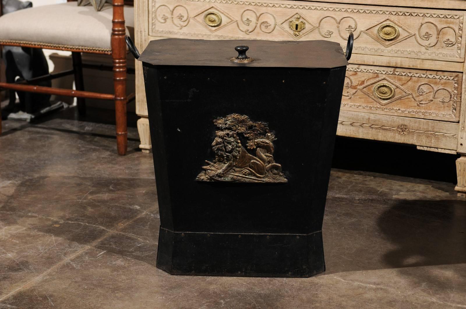 An English black painted metal coal hod with bronze lion from the late 19th century. This English coal hod or coal scuttle features a rectangular lid with canted sides and round pull, flanked on the sides by two round handles. (A hod or scuttle is