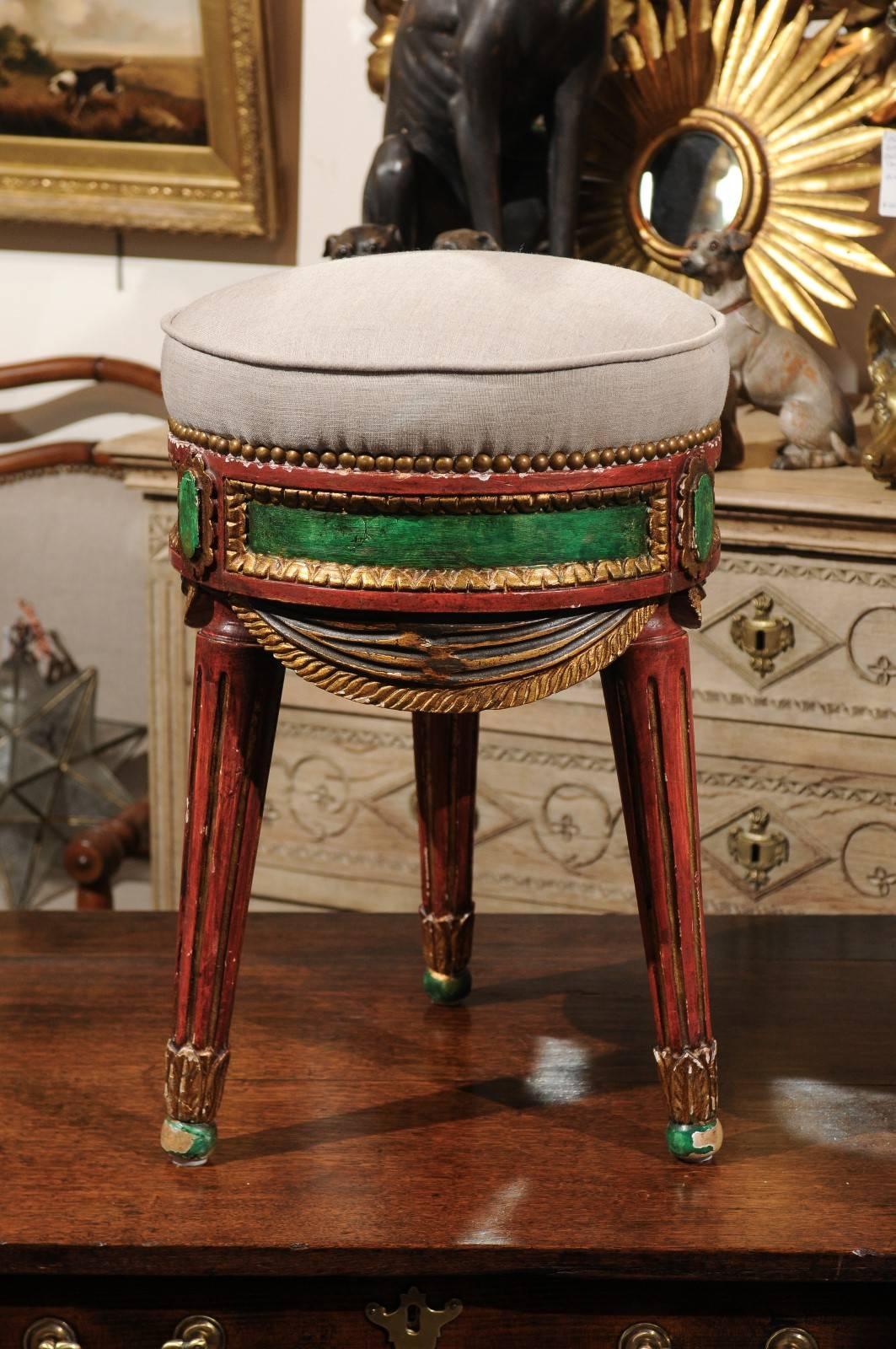 A Venetian painted and carved wood stool with upholstered seat from the mid-20th century. This Italian round stool was born in Venice in the 1950s. The circular seat is upholstered in linen with single welt with nailhead trim. The carved apron