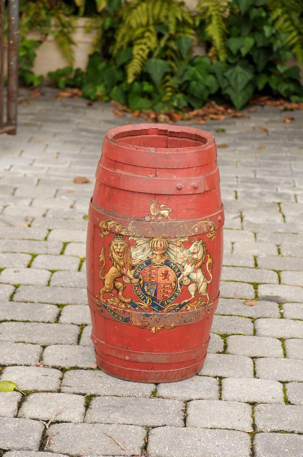 An English red painted wooden barrel umbrella stand with royal coat of arm from the early 20th century. This English barrel features a slender wooden body with iron straps, all painted in red. The front is adorned with the royal coat of arms made of