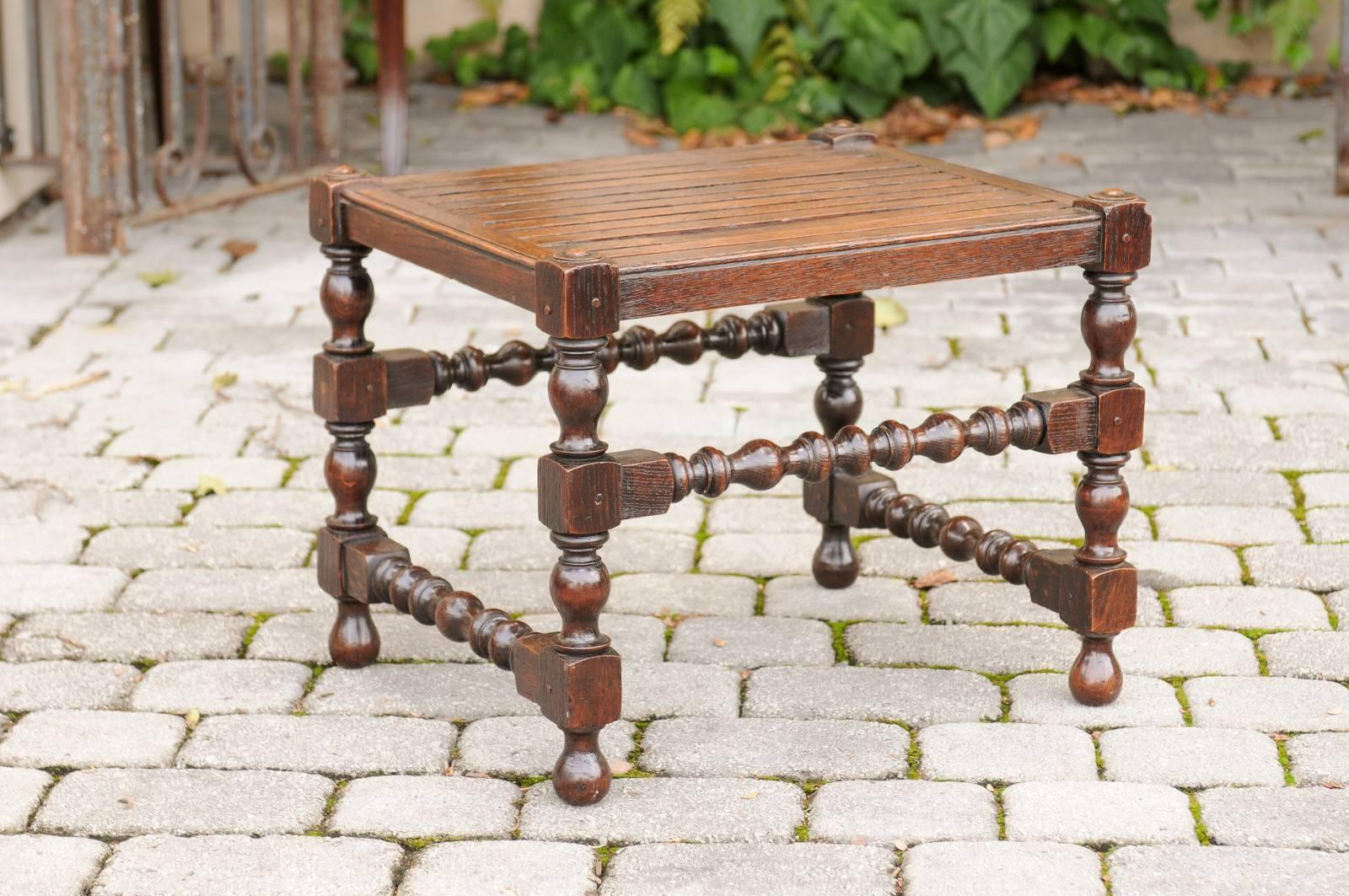 An English oak barley twist stool with slatted seat from the late 19th century. This English stool features a slatted wooden seat raised on four beautifully turned legs with barley twist side stretchers. Placed at different heights, these side