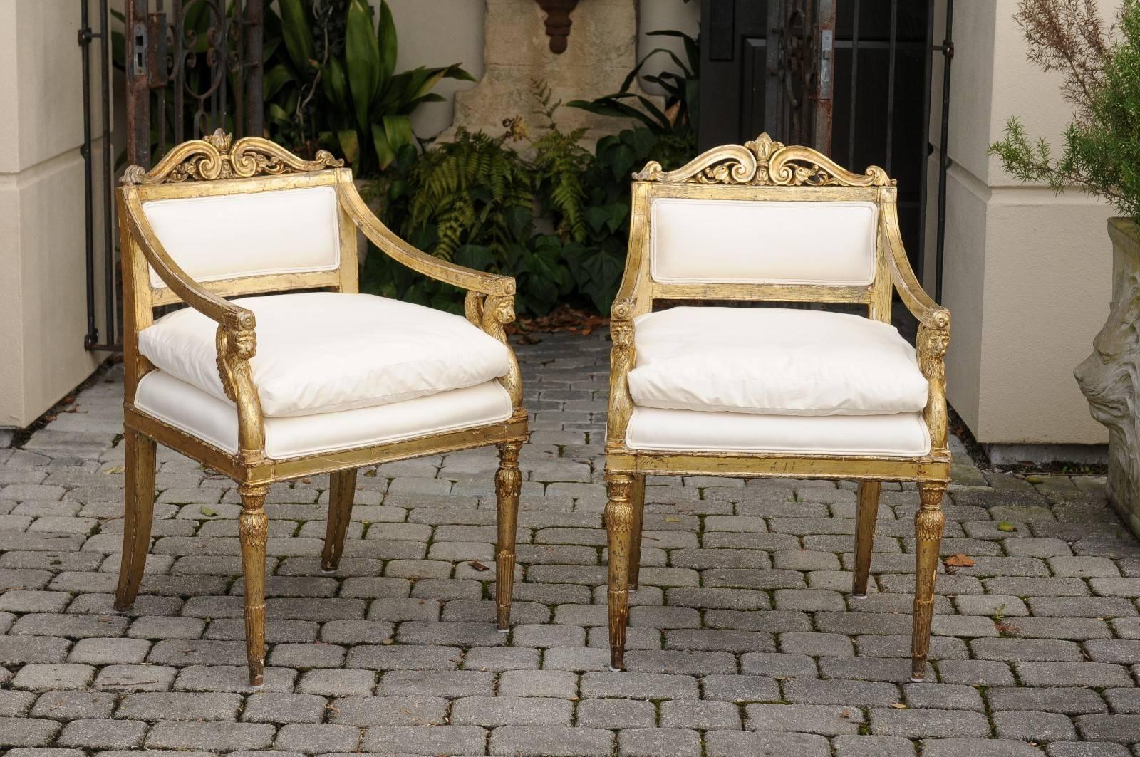 Pair of Italian neoclassical giltwood upholstered armchairs with winged lion motifs from the late 18th century. Each of this pair of Italian armchairs features a beautifully carved back adorned with a stylized fleur-de-lys, flanked with delicate