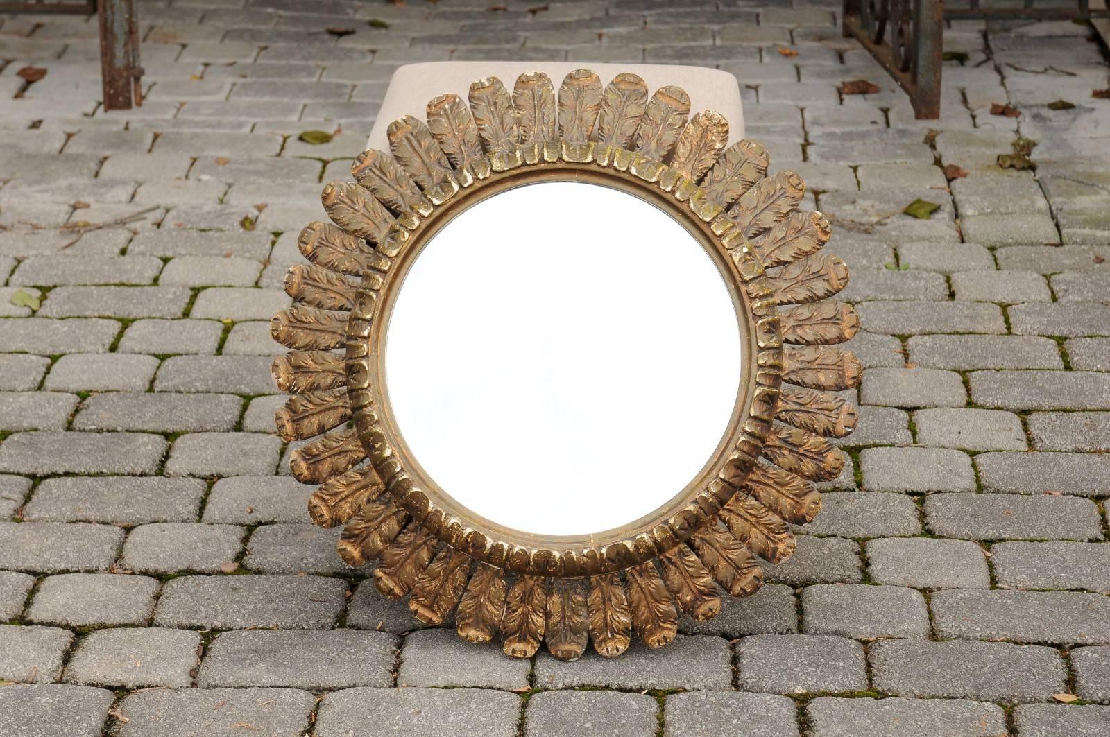 An Italian round carved giltwood mirror with foliage motifs from the mid-20th century. This Italian carved mirror features a cylindrical frame, adorned with leafy motifs. The clear glass is surrounded with a raised molding, to which are attached
