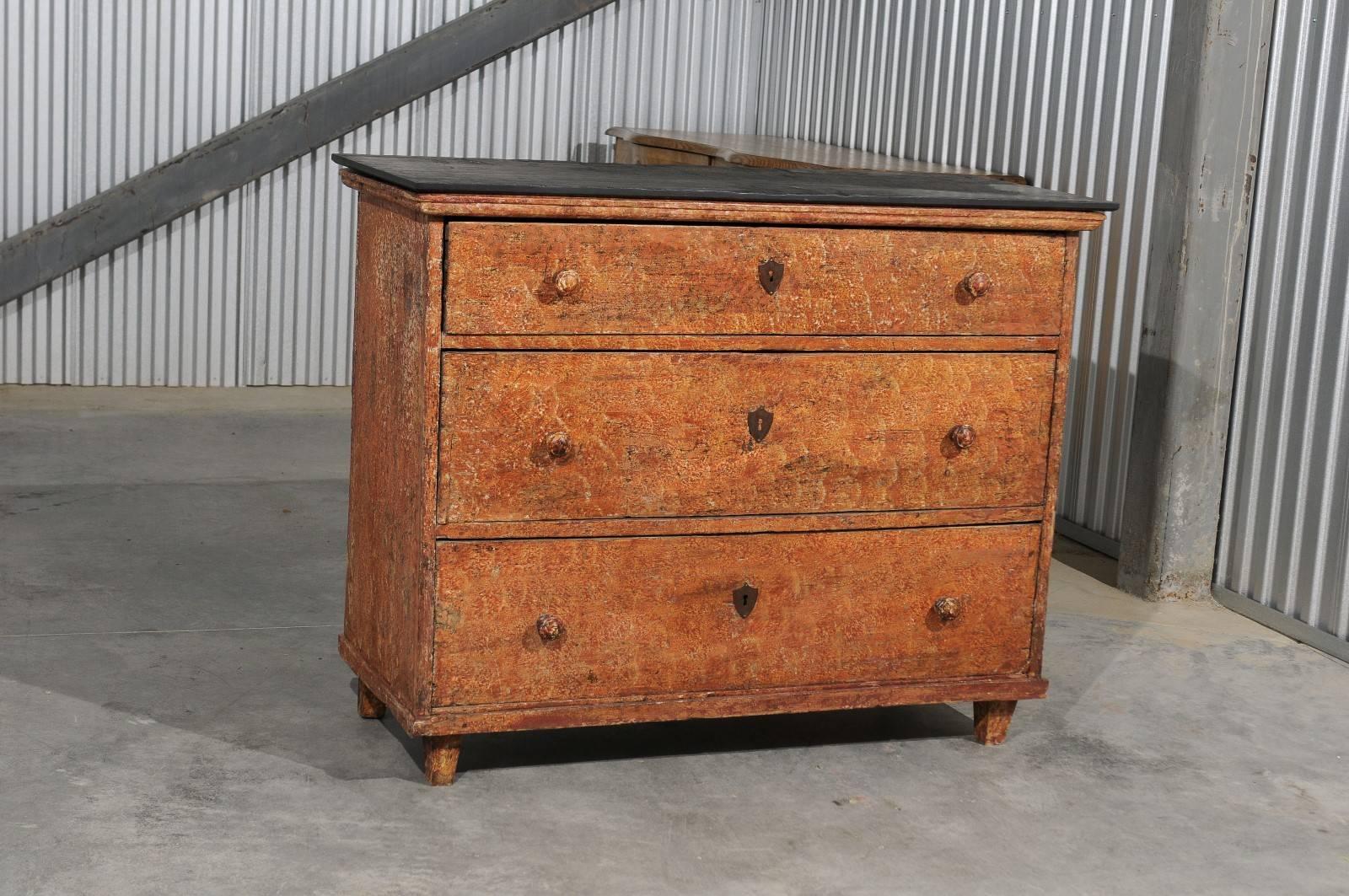 A French painted wood three-drawer commode from the early 19th century with black slate top. This French commode features a rectangular black slate top (not original to the piece), over three dovetailed drawers. Each drawer is adorned with two