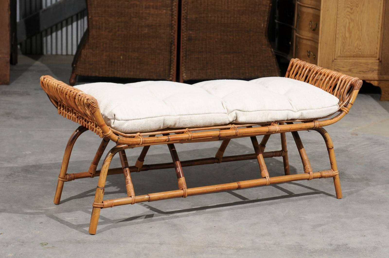 A French midcentury rattan low bench upholstered with Belgian linen cushion. This French rattan bench from the mid-20th century features a rattan structure made of simple curves. The rectangular seat is flanked by two curving arms. A new custom-made