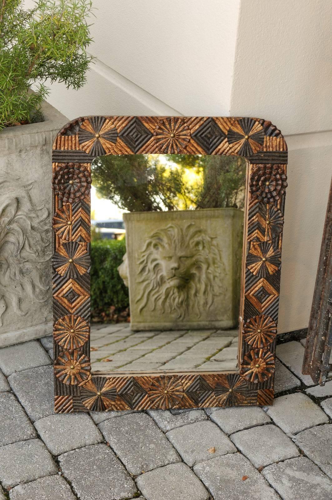 A French carved wood Folk Art mirror from the early 20th century. This French wall mirror features an unusual frame. While its Silhouette may remind us of Louis-Philippe mirrors with their rounded top corners, the uncommon décor has a Tramp Art