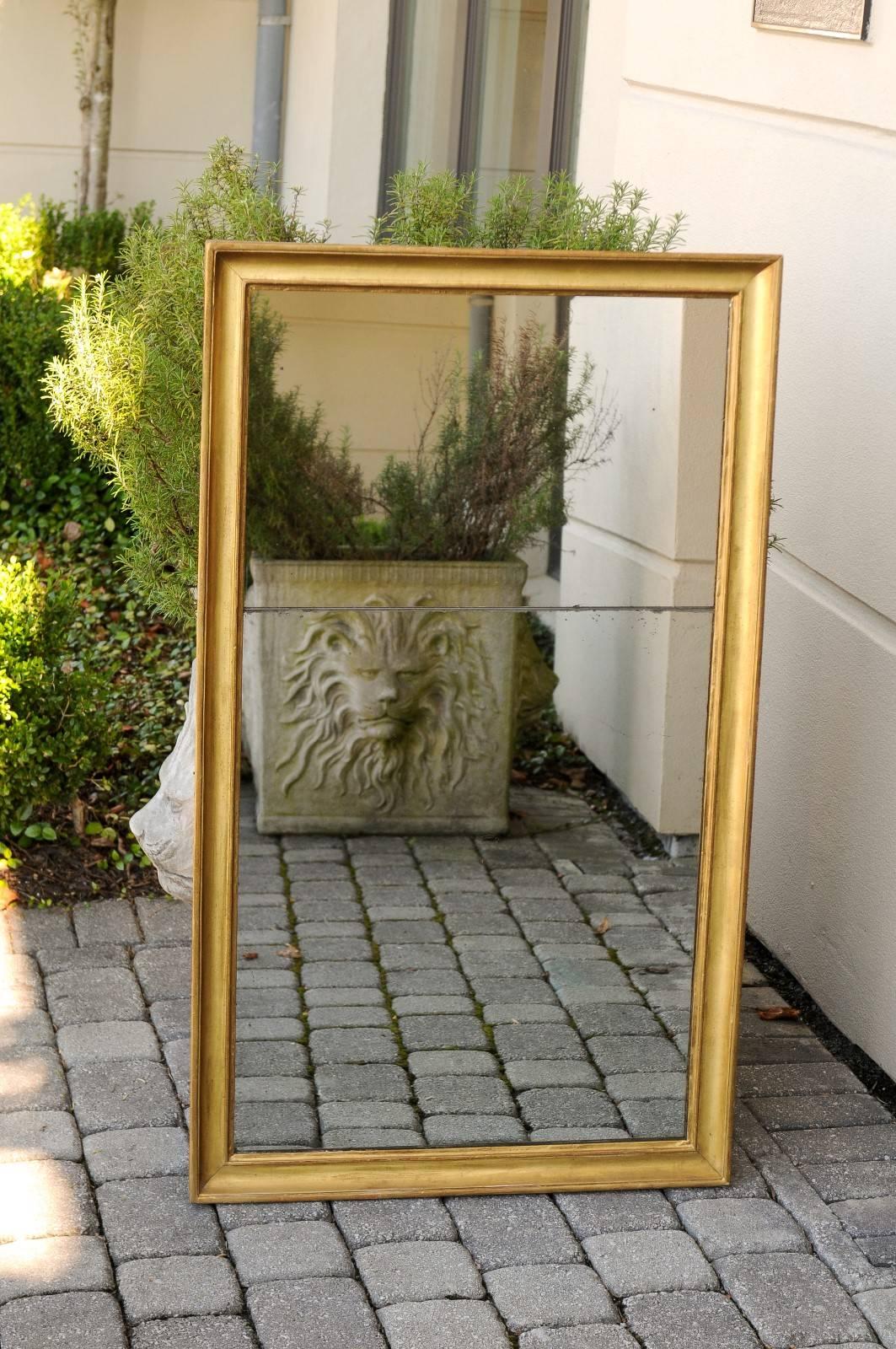 A French giltwood rectangular mirror with split glass from the early years of the 20th century. This French mirror, born in the turn of the century (19th to 20th), features a lovely linear giltwood frame, slightly concave on the inside. The mirrored
