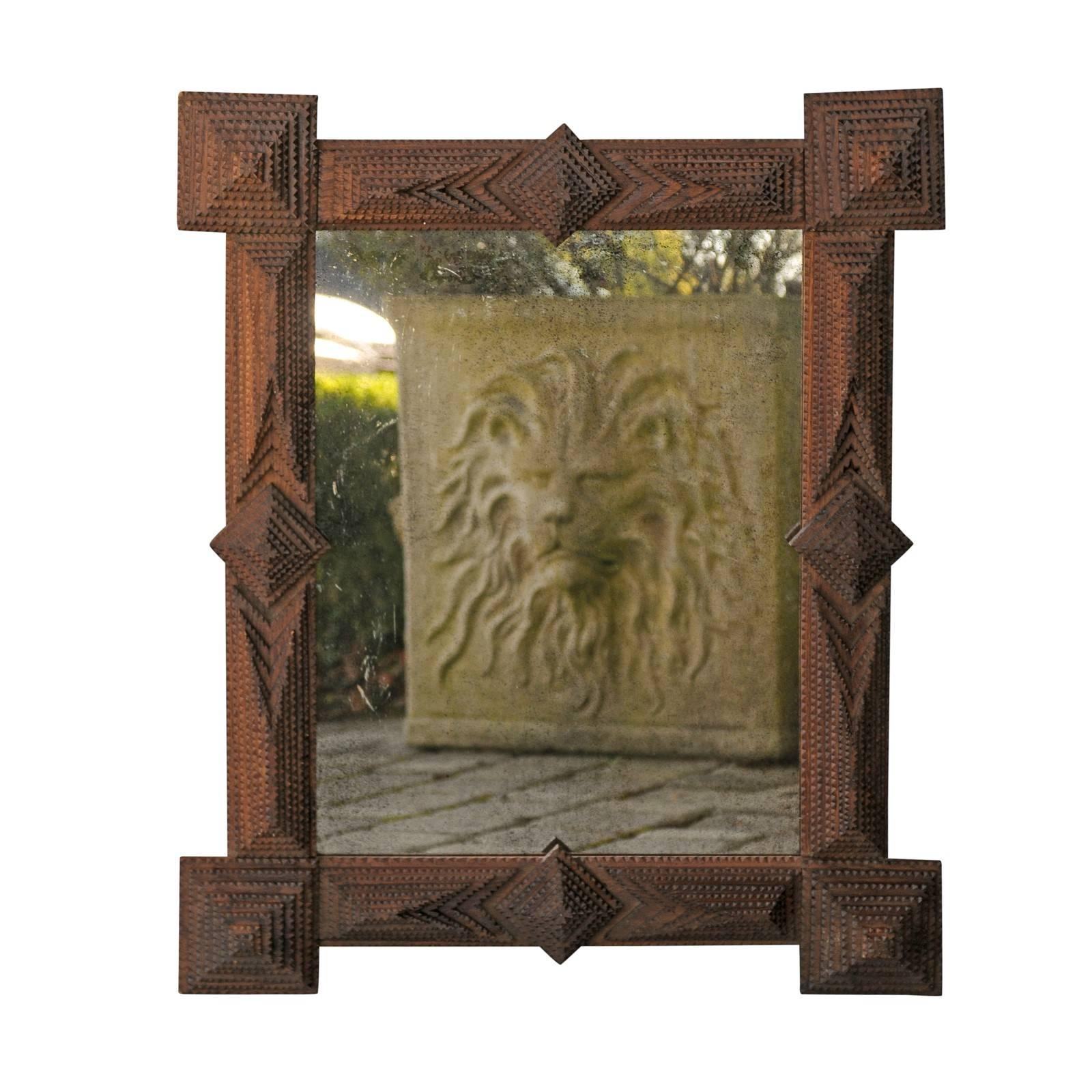 A French Tramp Art mirror with pyramidal motifs from the turn of the century. This French mirror was hand-carved in the early 1900s in the manner typical of the Tramp Art style. Consisting of a rather linear frame, the mirror features a layered