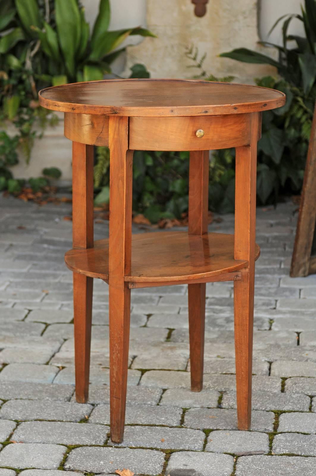 A French two-tiered side round side table with single drawer and tapered legs from the mid 19th century. This French side table was born in the 1840s, during the reign of Louis-Philippe, the last king of France. Featuring a circular top, the apron