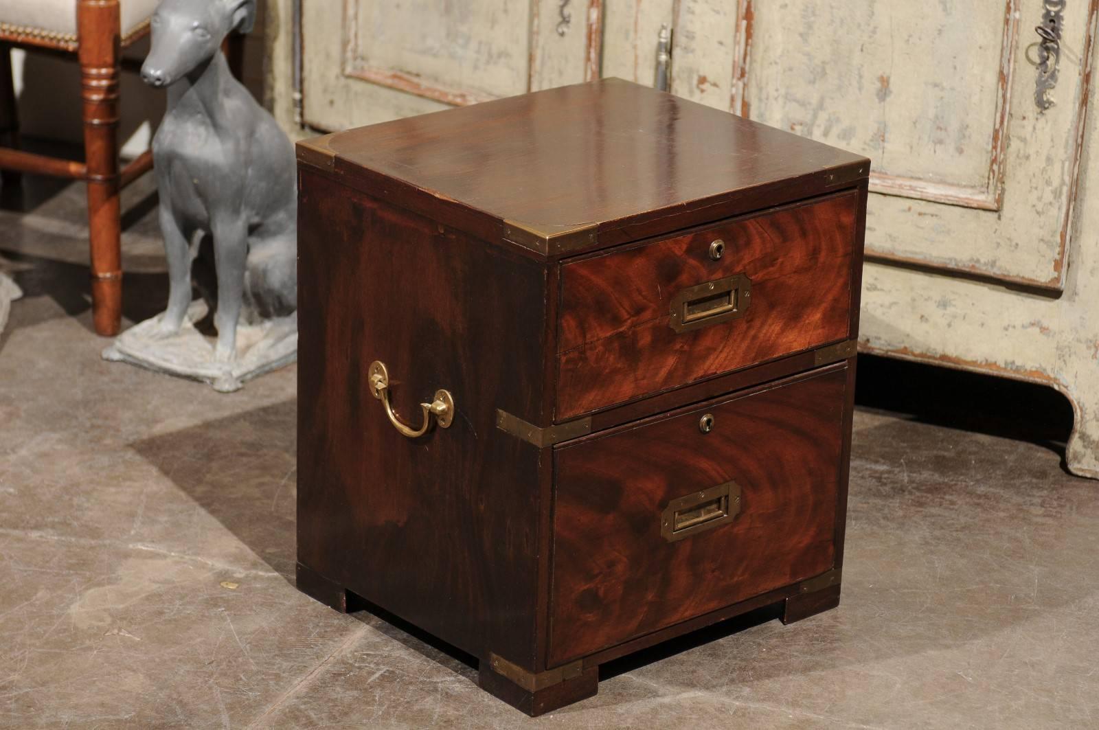 An English Campaign petite flaming mahogany chest / box with brass fittings from the late 19th century. This English box features a simple, linear frame, stylishly accented by brass fittings on the surround. The two dovetailed drawers in the front