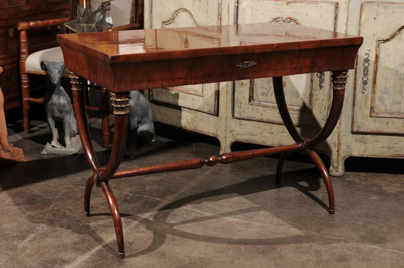 An Italian mahogany Empire Revival desk with frieze drawer and curule base from the 1930s. This Italian writing table features a rectangular top sitting above a single frieze drawer. The table is raised on X-frame base, made of crossing cornucopias,