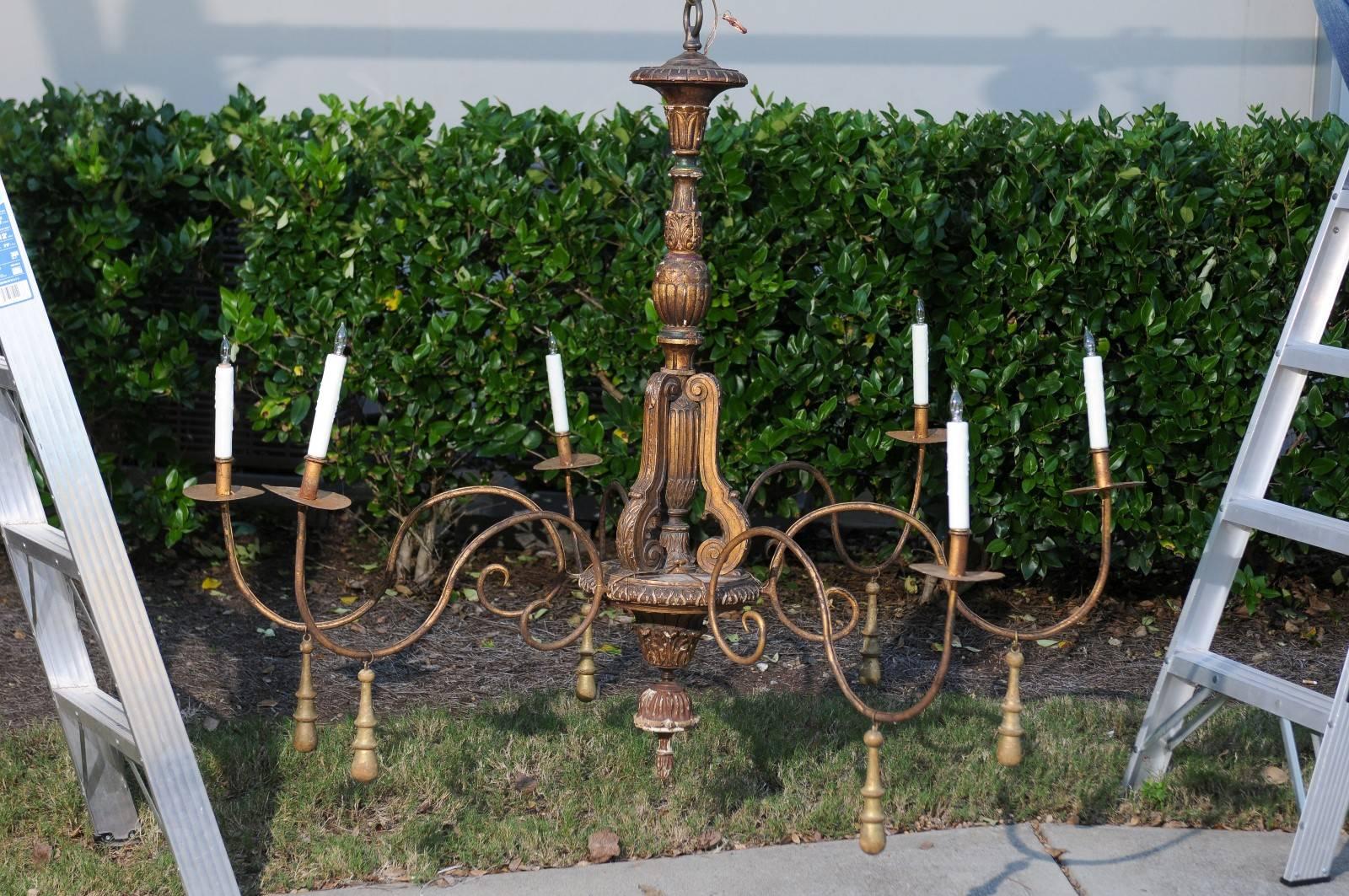 An Italian six-light parcel-gilt wooden chandelier with swoop arms from the 19th century. This Italian chandelier features a central carved wooden column, adorned with acanthus leaves, waterleaves and gadrooned motifs placed above Baroque looking