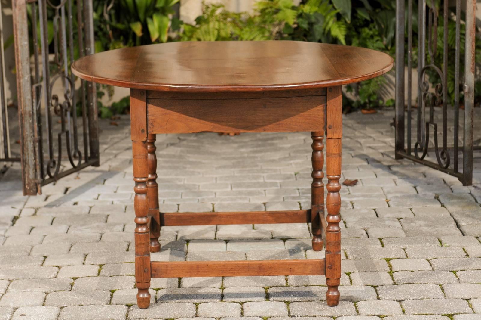 A French round walnut centre table with turned legs and stretcher from the late 19th century. Born in the 1880s, this French walnut table features a circular top supported by a simple square-shaped apron. Four elegant turned legs supporting the