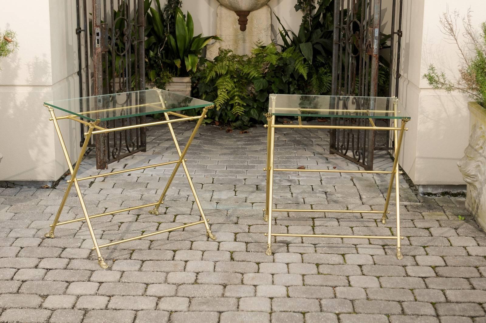 A pair of 1960s Italian brass and glass folding side tables with cast brass hands and sandaled feet. Each of this pair of Italian Mid-Century Modern side tables features a 0.25