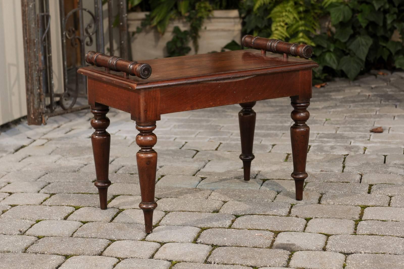 An English petite mahogany hall bench with cylindrical supports and turned legs from the second half of the 19th century. This English hall bench features a rectangular single planked seat, flanked with cylindrical lateral supports. The bench is