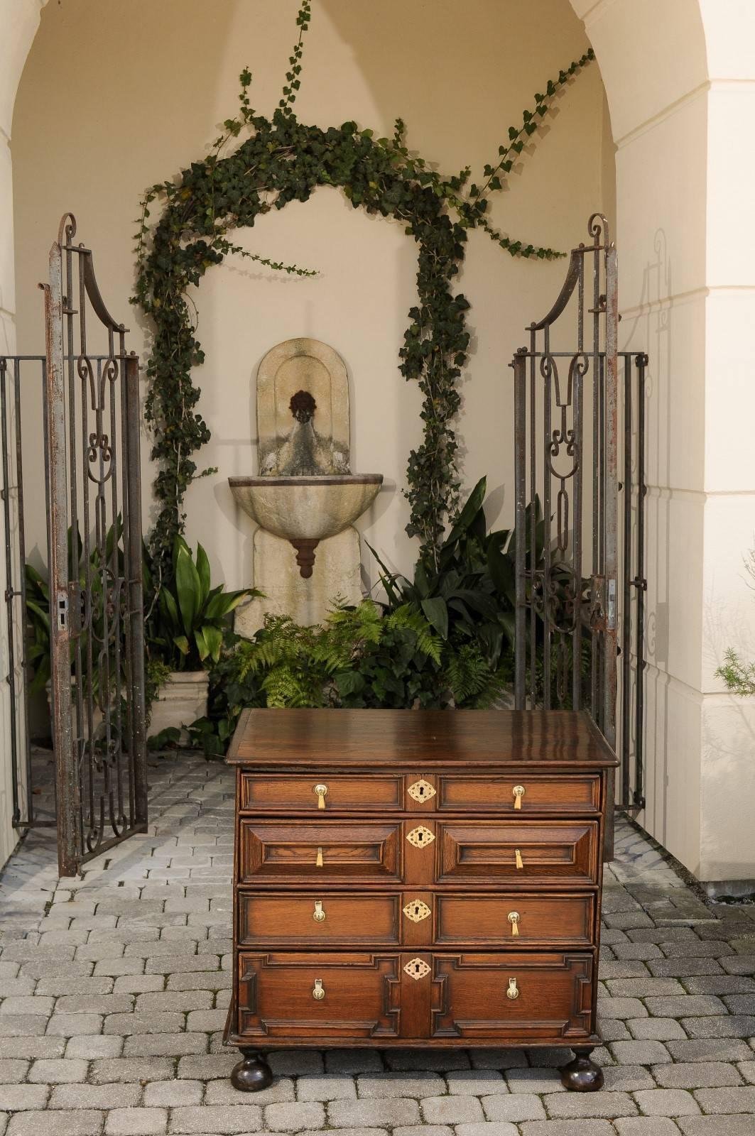 An English George III period four-drawer commode with geometric front from the late 18th century. This English four-drawer commode features a rectangular top with rounded edges and darker frame, overhanging four drawers. The eye is immediately drawn