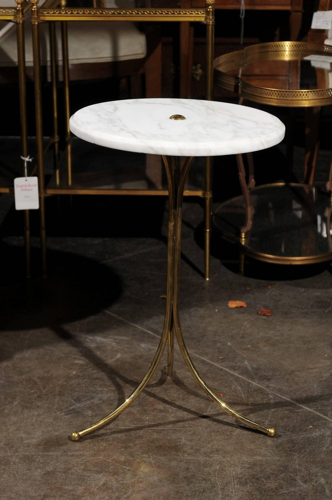 An Italian marble and brass drinks table from the Mid-Century Modern period. This Italian drinks table features a circular white marble top sitting above a brass pedestal base with splayed tripod base. The beauty of the marble top is only