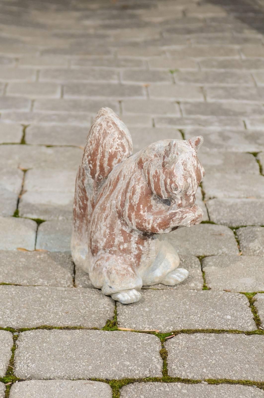 An English painted lead animal sculpture of a squirrel from the first half of the 20th century. This sculpture features a sweet squirrel with a nicely weathered appearance due to its presence outdoors, voraciously eating what is most likely a nut.