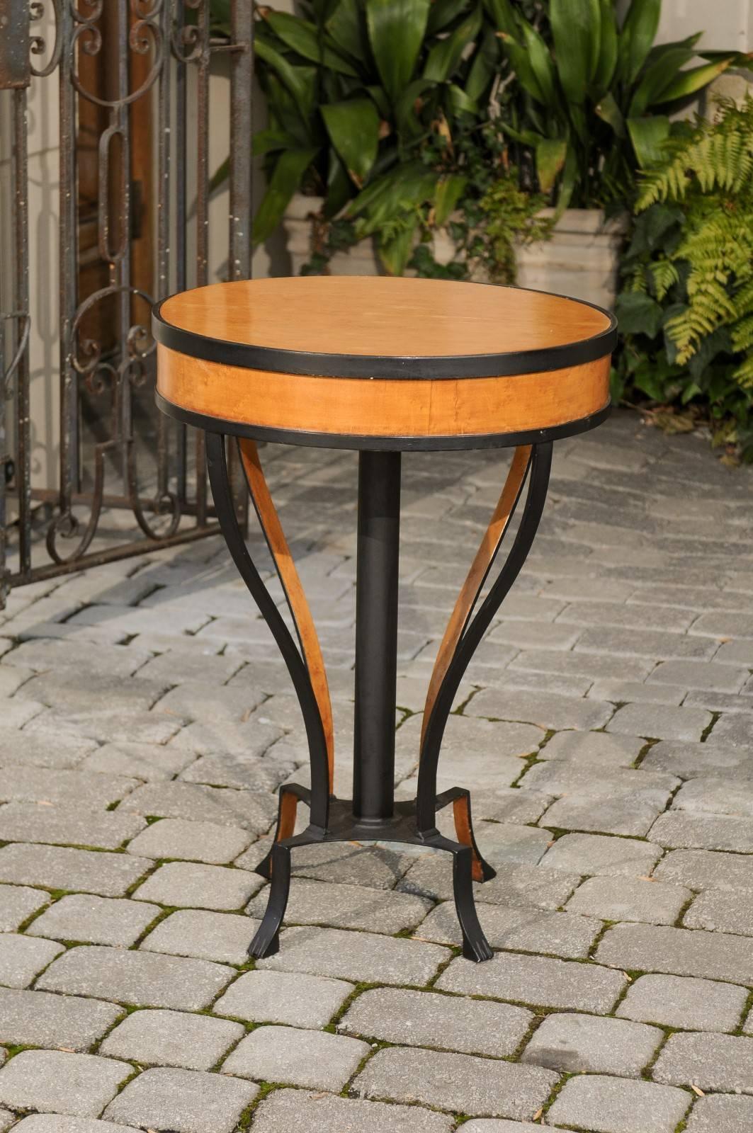 An Austrian Biedermeier period guéridon side table with burl veneer and iron base from the early 19th century. This Biedermeier guéridon features a circular top made of burl veneer, accented by a black iron armature. This alternating pattern is