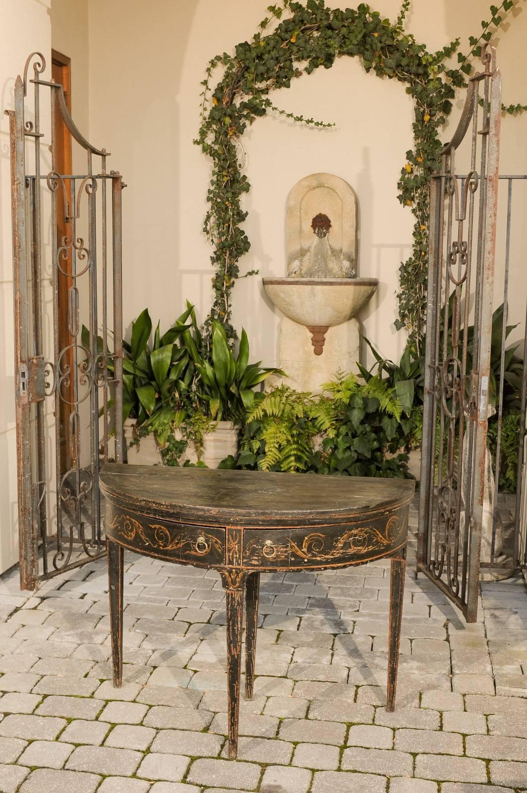 An Italian Neoclassical period demi-lune gateleg console table with flip top, Vitruvian scroll frieze and two drawers from the early 19th century. This exquisite Italian demilune table features a semi-circular flip top, that opens up to double in