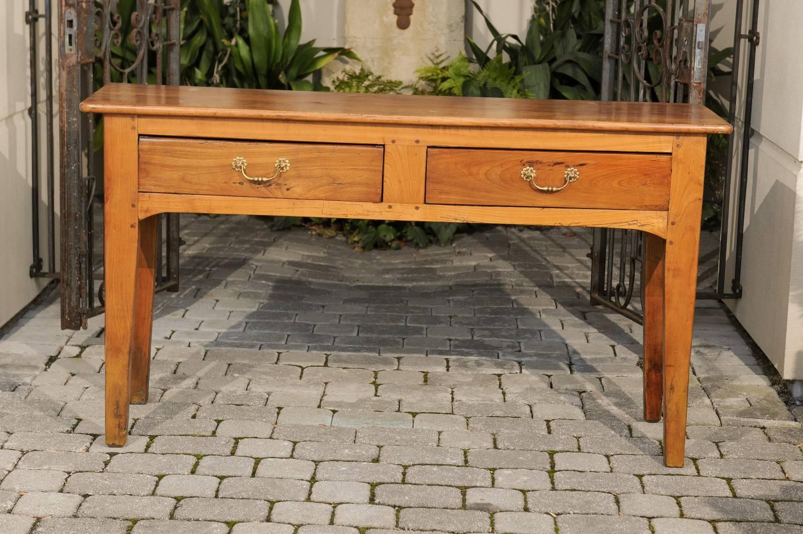 A French two-drawer fruitwood server with peg construction and tapered legs from the late 19th century. This French wooden console table features a rectangular planked top with rounded edges sitting above two drawers with brass bail handles and