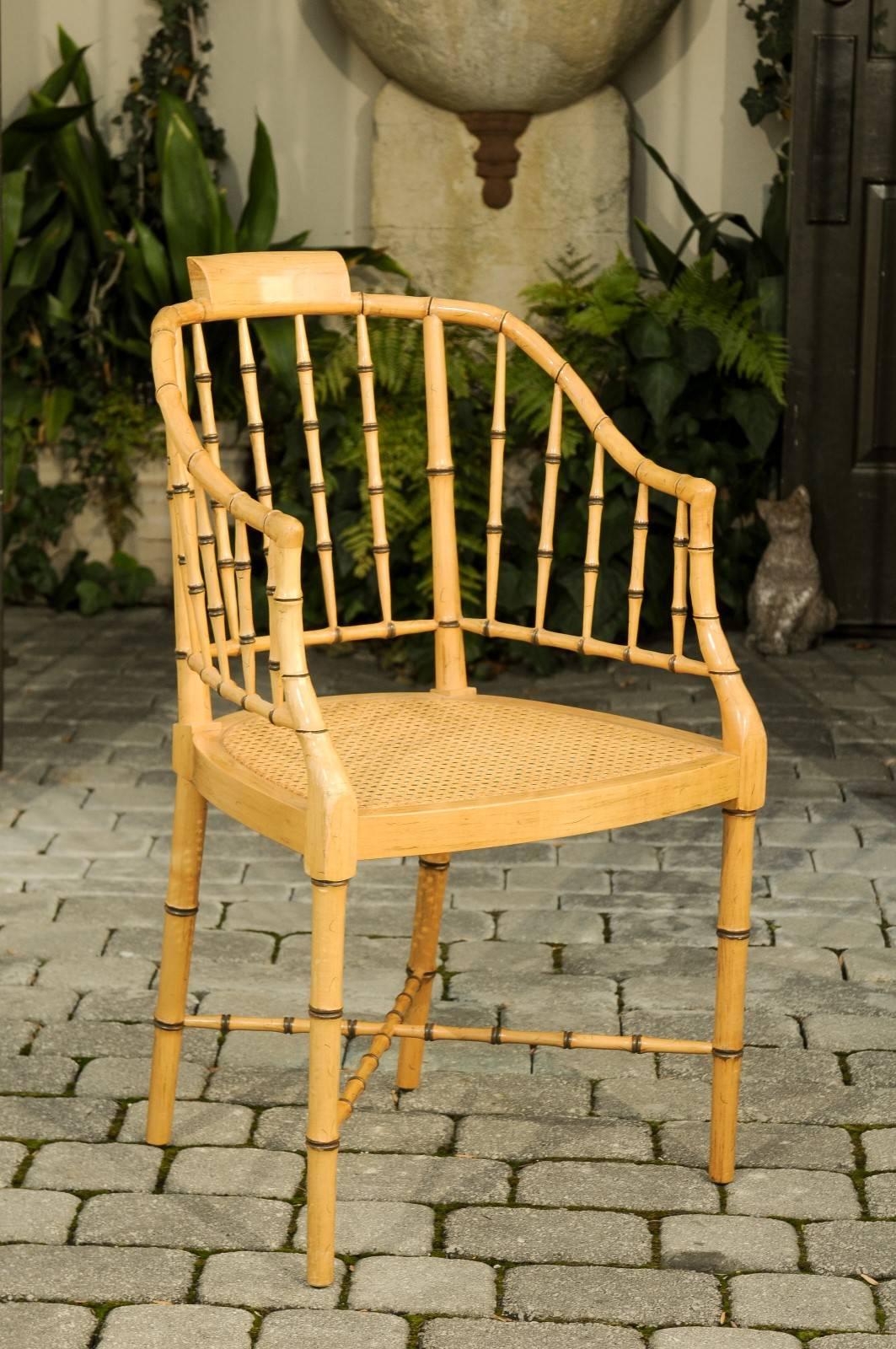 A vintage Mid-Century Modern faux-bamboo tub armchair from furniture maker Baker with cane seat. Made of faux-bamboo, this American Baker chair, circa 1960 features a tub shaped back and curved arms resting on a cane seat. The chair is raised on
