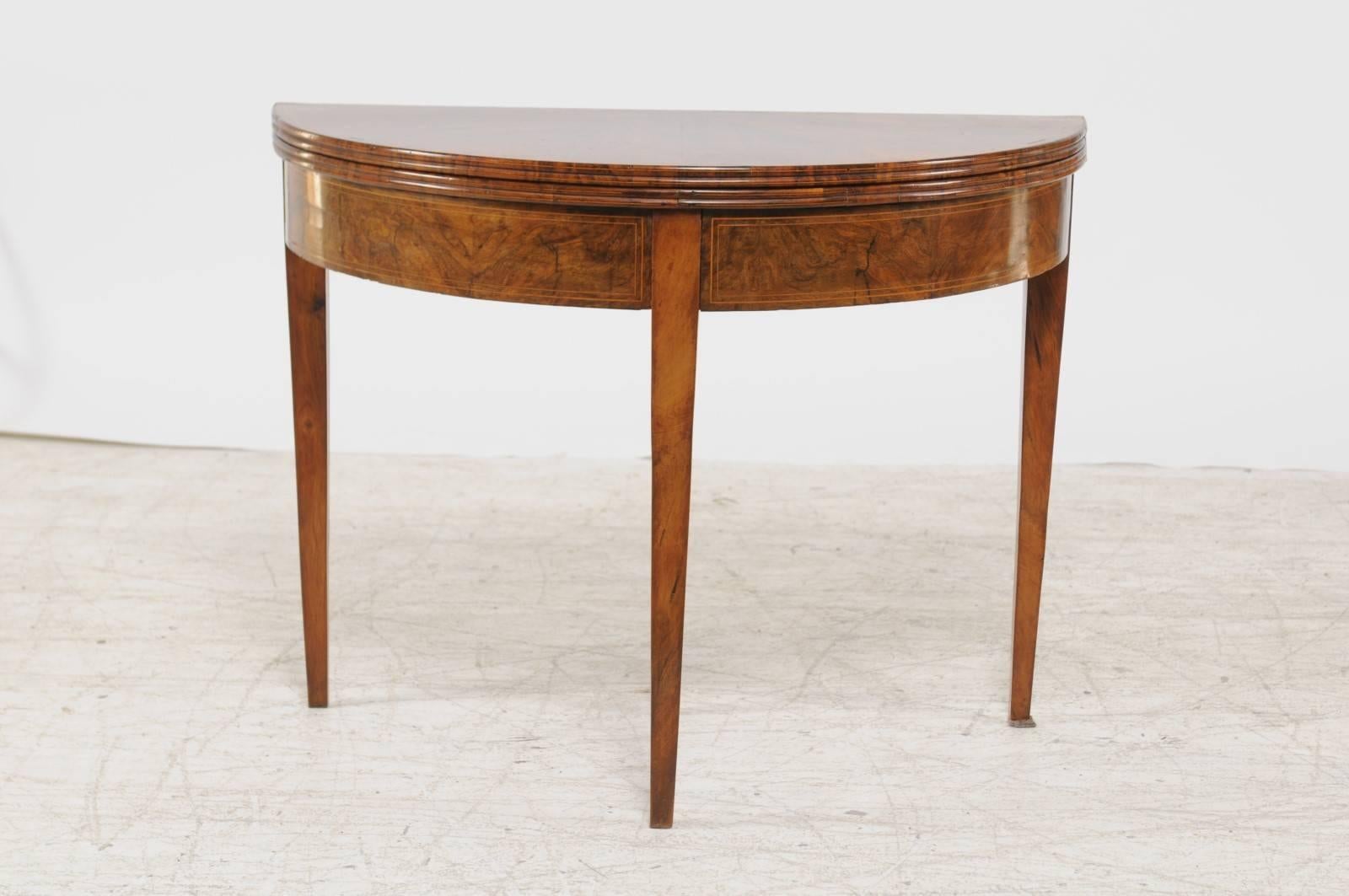 A French burled walnut demilune console table with quarter-veneered fold-over top, banded inlay and tapered legs from the late 19th century. This French demilune table features a semi-circular top, adorned with an exquisite quarter veneer,