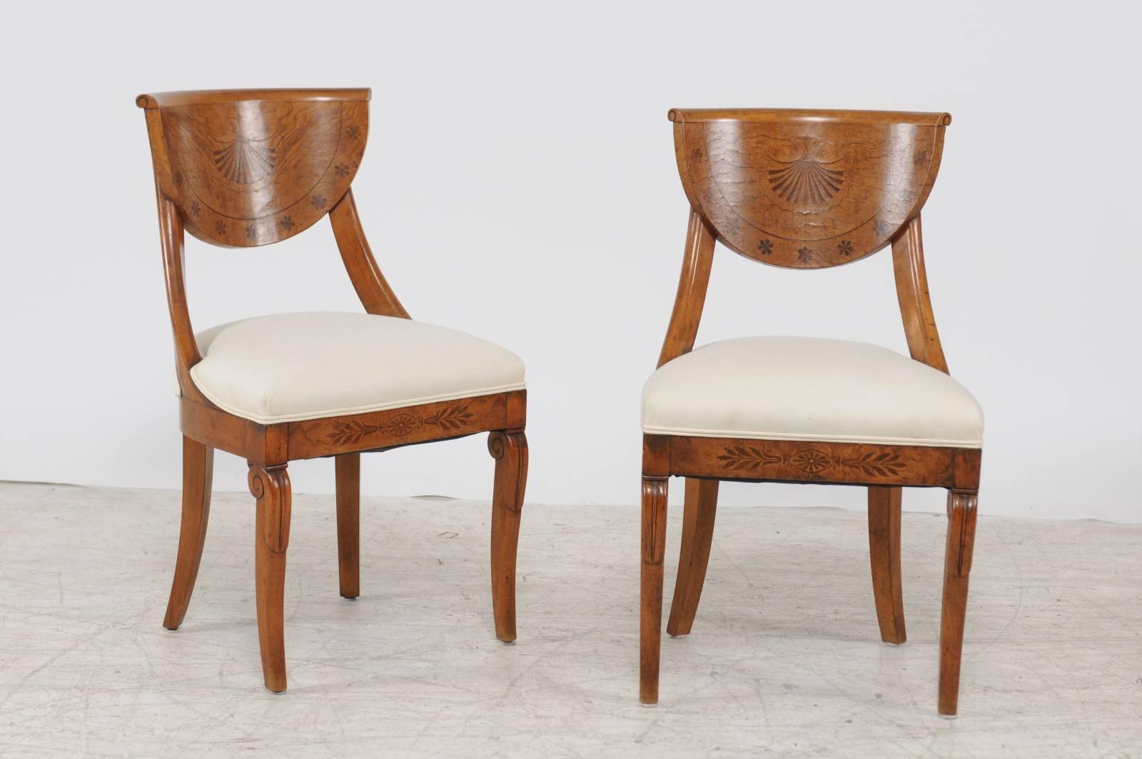 A pair of Austrian Biedermeier chairs with marquetry inlay from the mid-19th century. Each of this pair of Austrian side chairs features an exquisite half-moon curved back, topped with a slightly out-scrolled rail and adorned with delicate marquetry