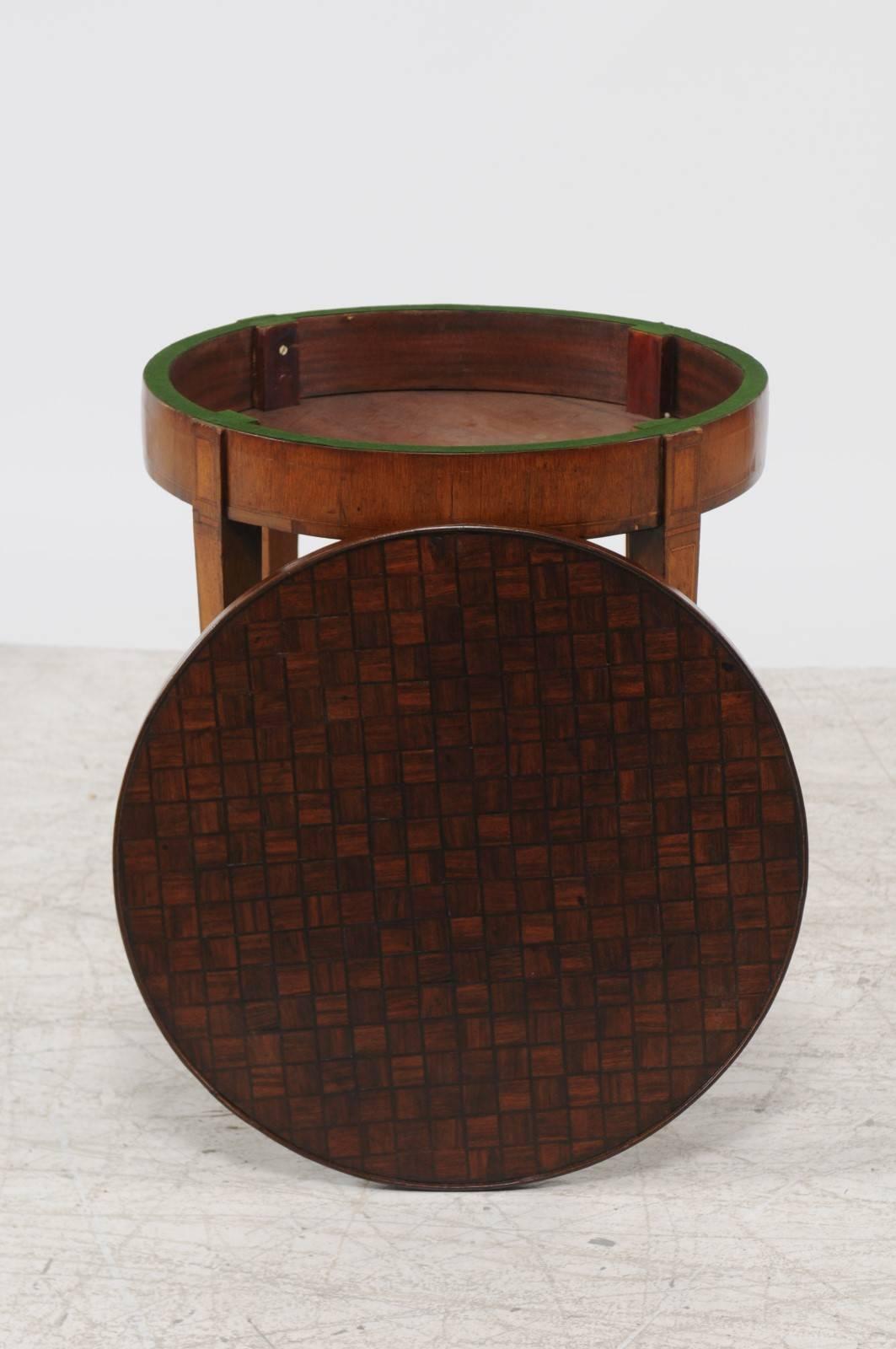 A French Louis XVI style round parquetry top game table with flip top and tapered legs from the second half of the 19th century. This French table features a circular parquetry top that flips to reveal a green felt lined side perfect for a game