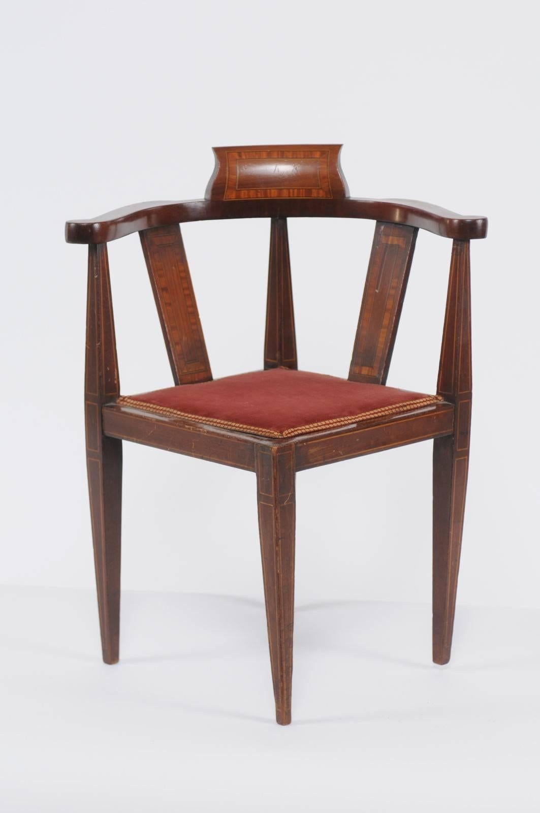 A French mahogany child corner chair with banded inlay from the turn of the century. This French corner child chair features an exquisite mahogany structure, delicately adorned with a crossbanded inlay, alternating with a discreet banding. The seat