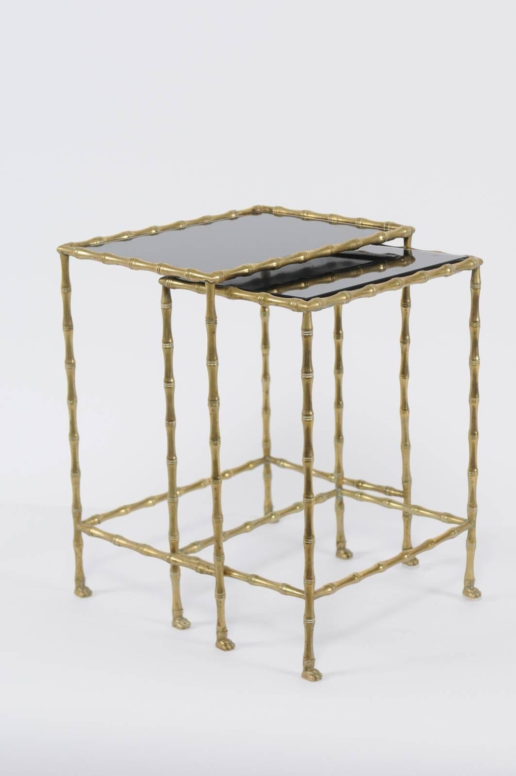 A pair of French vintage brass and black stone nesting tables with lion paw feet from the mid-20th century. Each of this pair of 