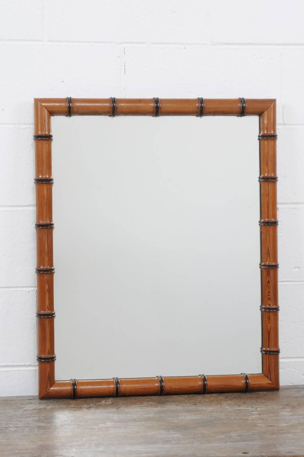 An English faux-bamboo rectangular mirror with ebonized wood accents from the late 19th century. This English mirror features a rustic faux-bamboo frame, rhythmically accented by dark ebonized wood highlights. The mirror plate is clear, allowing