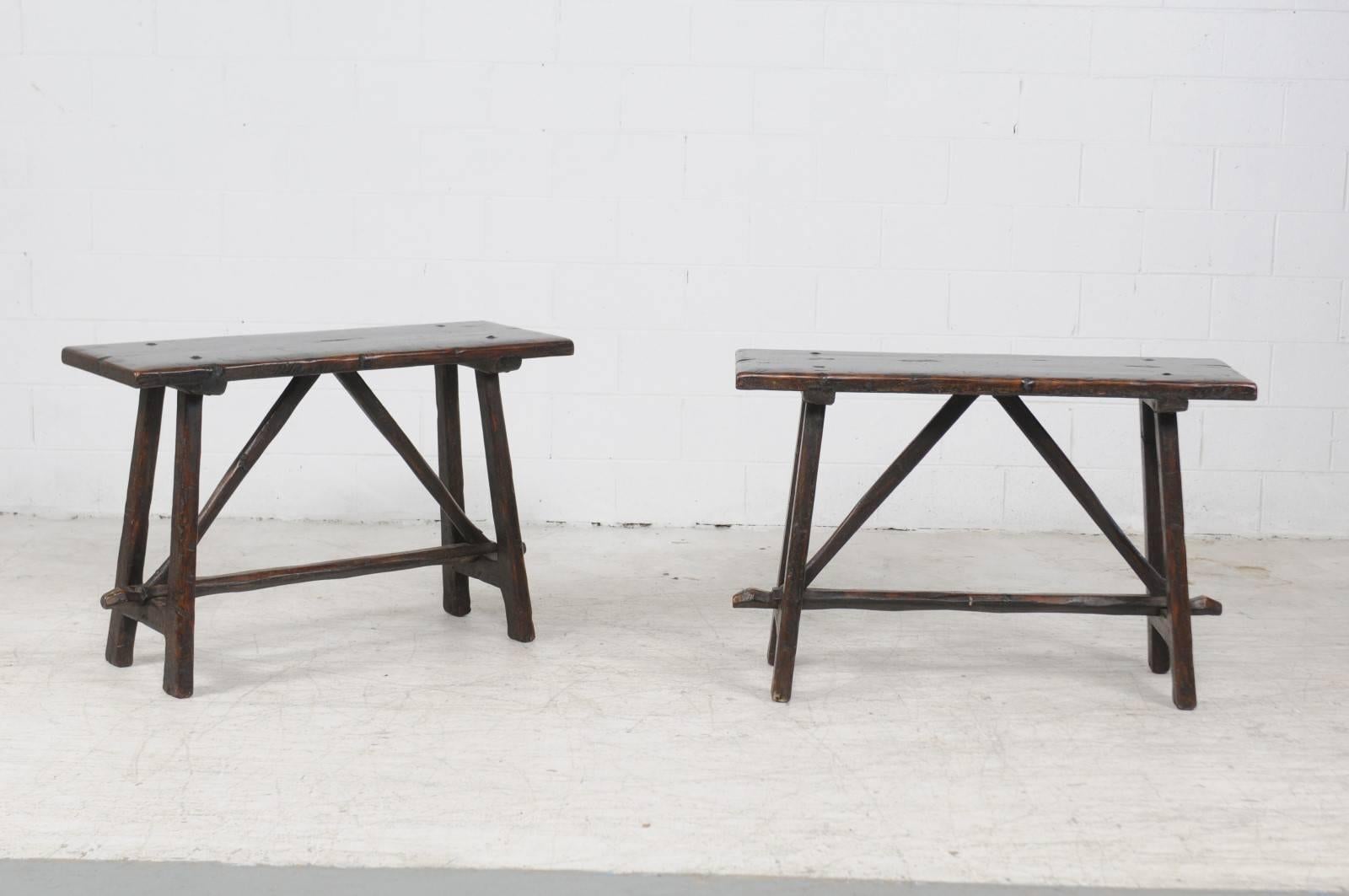 A pair of Italian walnut console tables from the early 19th century. Born during the early years of the 19th century, each of this pair of Italian console tables features a rectangular top sitting above a trestle base with splayed legs, connected to