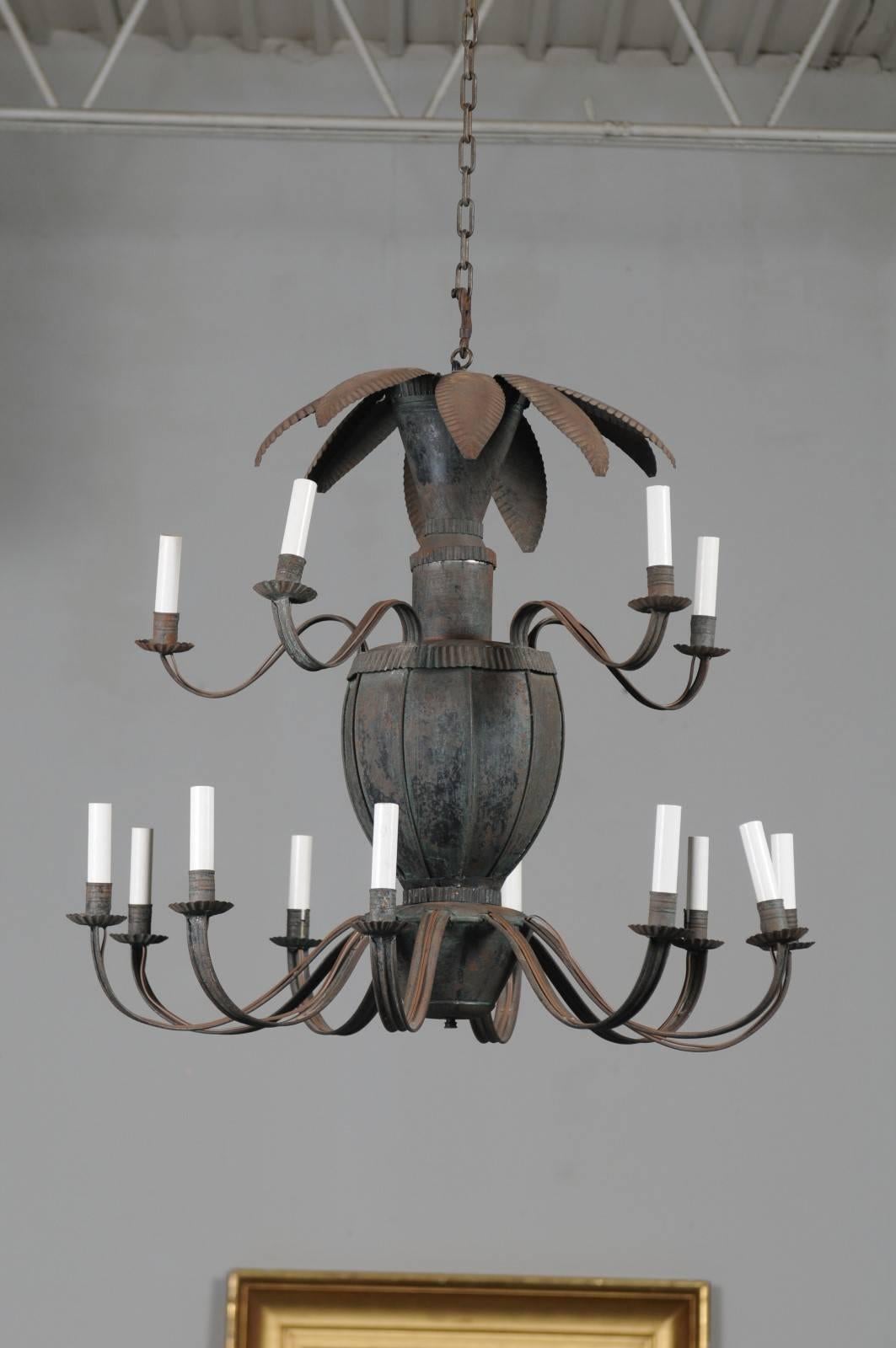 A French painted tole 14-light chandelier with central basket, scrolled arms and leaf motifs from the late 19th century. This French tole light fixture features a vertical silhouette made of a central metal basket, supporting 14 lights distributed