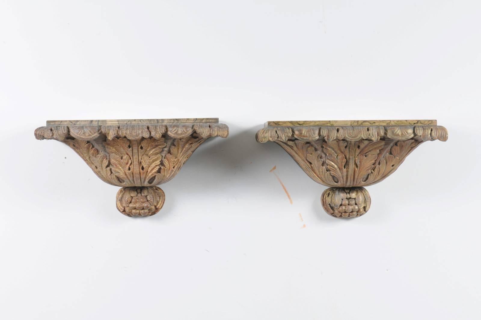 A pair of Italian richly carved giltwood wall brackets rom the second half of the 19th century with faux-marble painted tops. Each of this pair of Italian wall brackets features an exquisite carved body, skillfully decorated with gilded acanthus