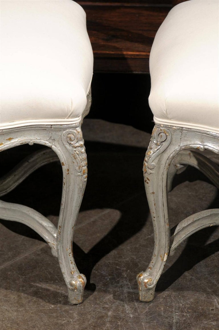 Muslin Pair of French Louis XV Style Silver Leaf Stools with Carved Cross Stretcher For Sale
