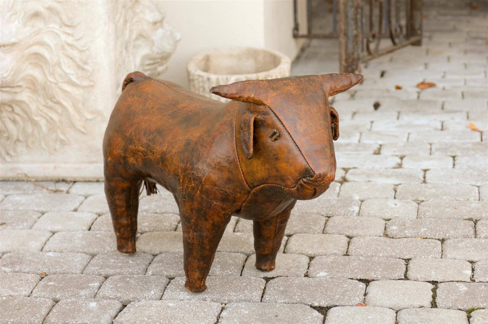 An English vintage bull leather foot stool. This exquisite English foot stool from circa 1960 features a small bull with straight horns. This sturdy four legged prize communicates strength and is made of stitched brown leather. Although a tremendous