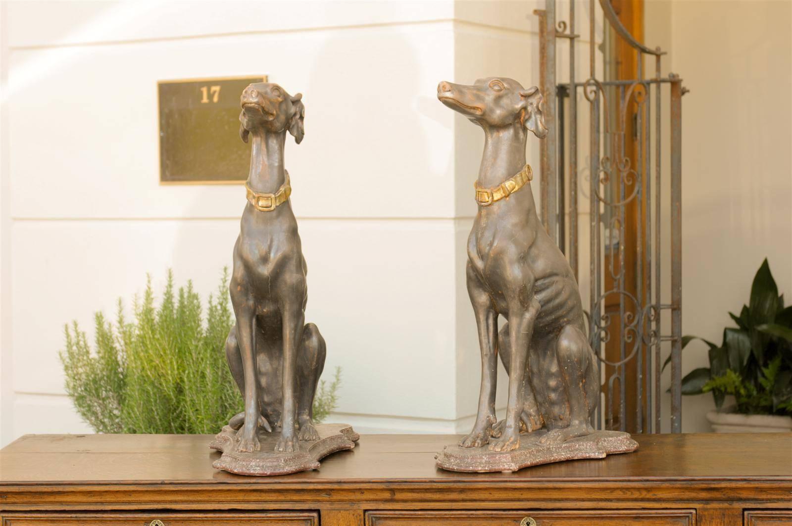 This pair of tall Italian greyhound sculptures from the late 19th century features the lean, muscular dogs, sitting quietly on painted faux-marble bases. Painted in grey, a skillful attention has been brought to the details, such as their head,