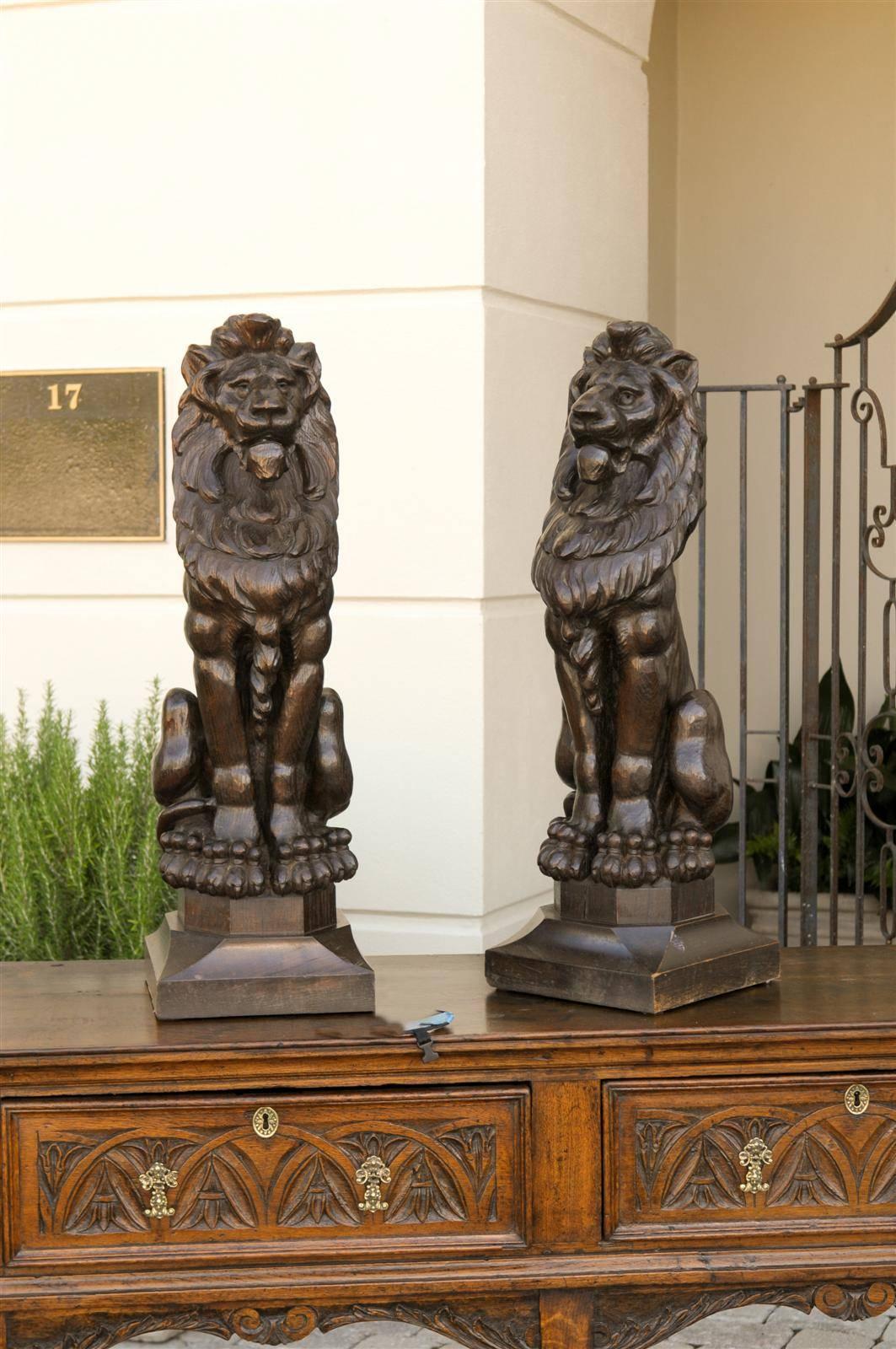 A pair of large English wooden carved lions from the late 1800s. These large English lions from the late 19th century are made of carved wood. The precision of the carving is quite impressive, the lions' manes are very detailed, and the instrument