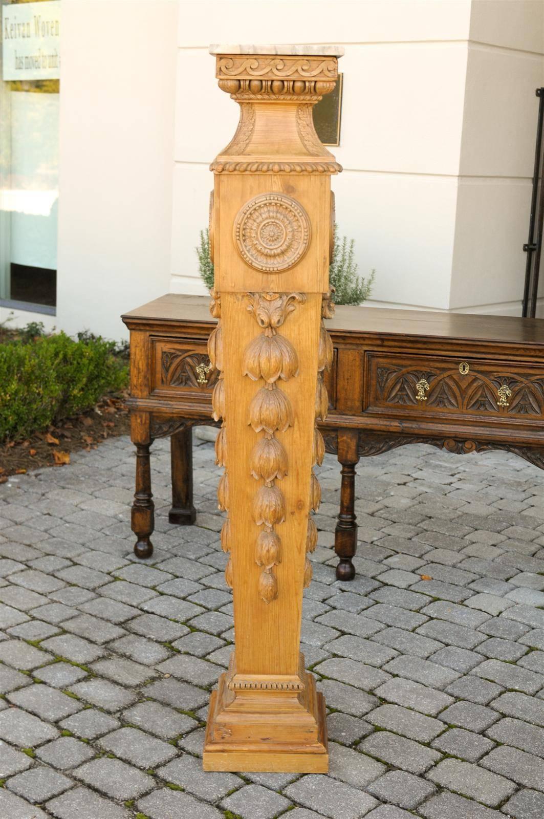 This pair of tall English Neoclassical style carved pine pedestals from the second half of the 19th century features exquisite square shaped marble tops over slender tapered, wooden bases. Just below the marble top, a Vitruvian scroll (also called