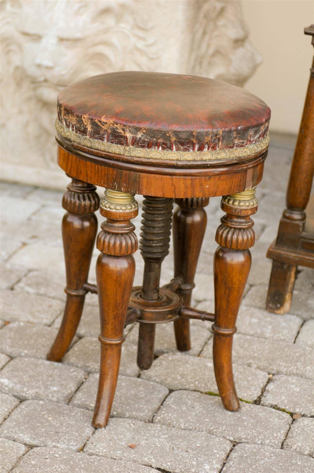 An English Regency Stool with a round, adjustable red leather seat. This spectacular English stool sits firmly on four splayed legs decorated with gadroon motifs on the top and secured by a cross stretcher. The seat on this circa 1830 stool is