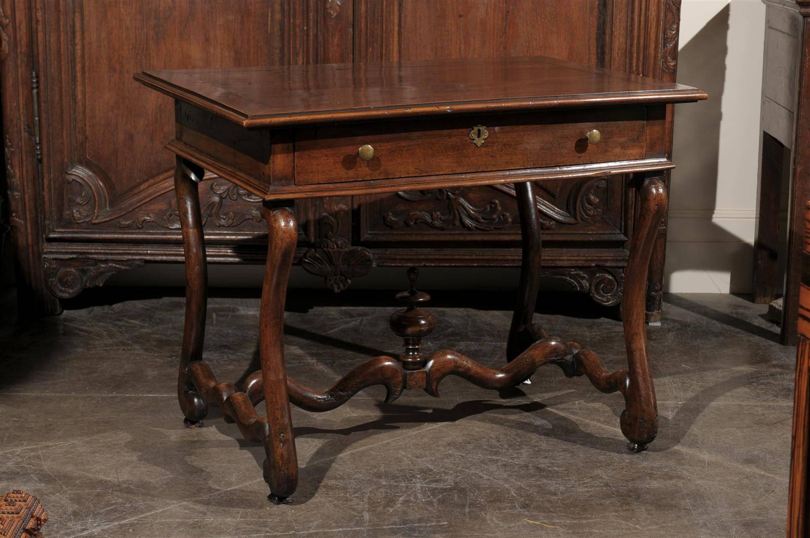 A French mid-19th century walnut side table. This French table from circa 1860 features a rectangular top over a single frontal dovetailed drawer with brass pulls. The table is raised on two lyre shaped legs, connected to each other by an