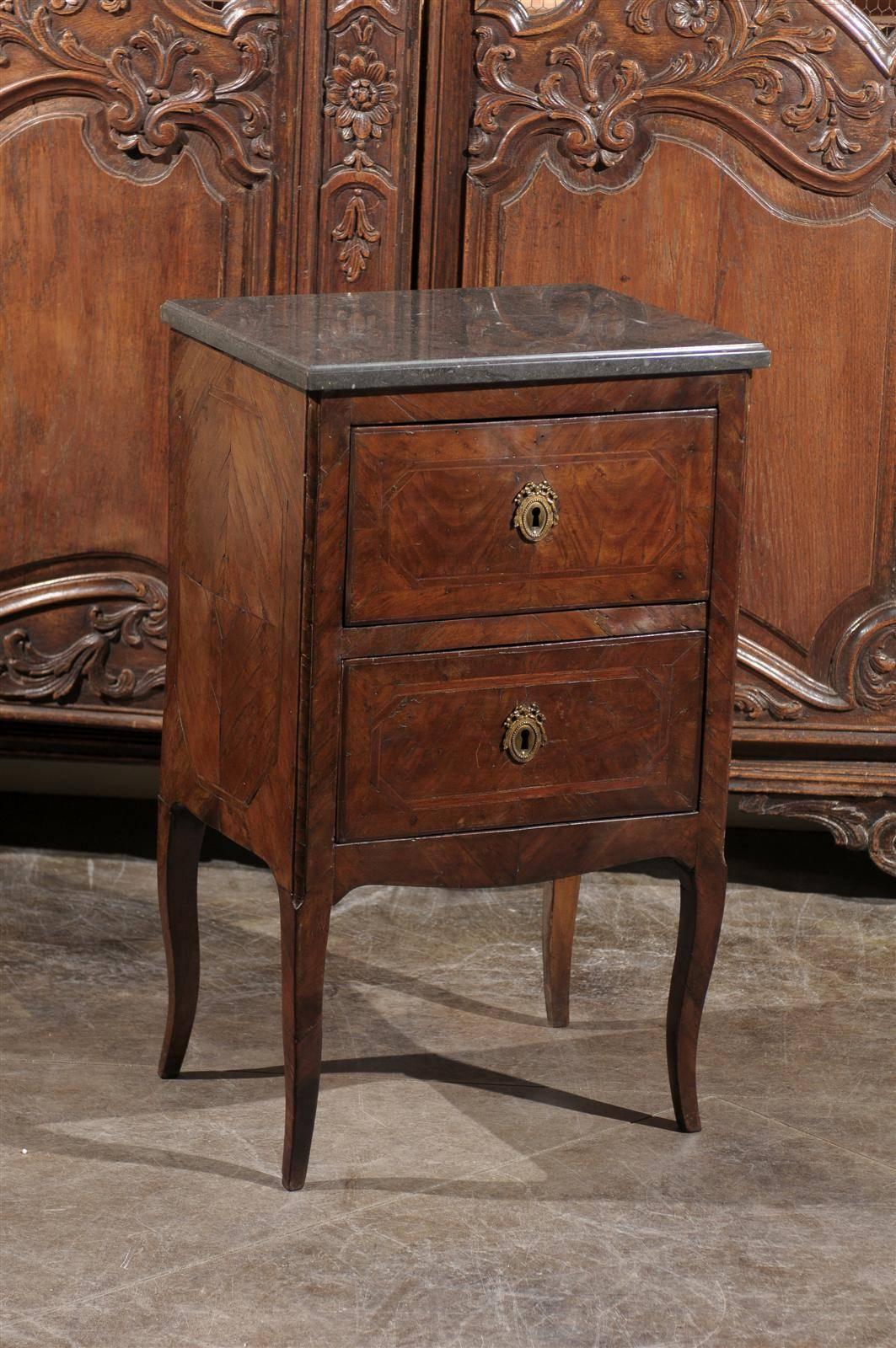 This petite Italian commode from the early 19th century features a rectangular dark grey marble-top over two drawers. The sides are decorated with a quarter veneer surrounded by an octagonal banded inlay. Each drawer, also adorned with the same