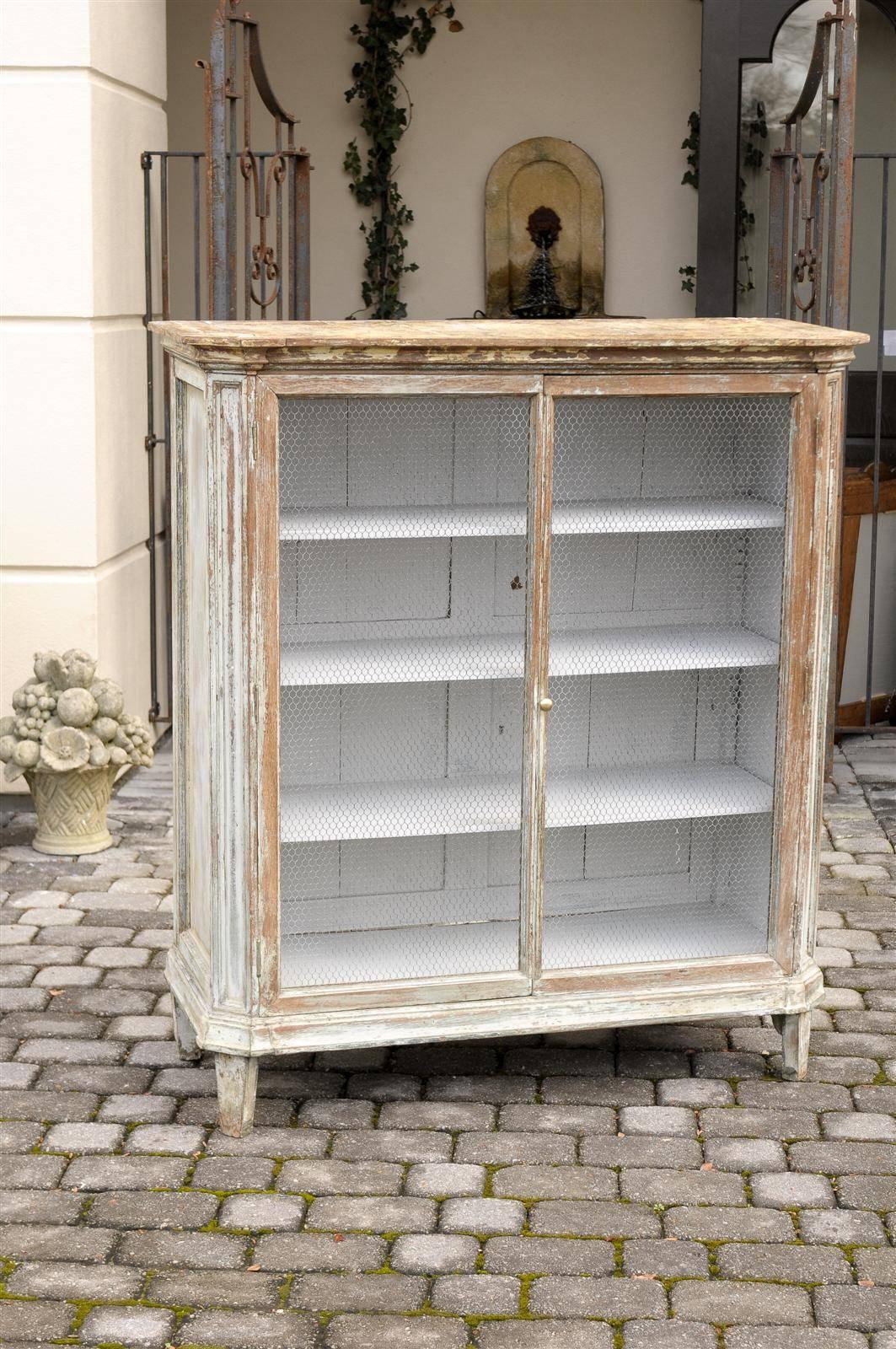 This French painted wood cabinet from the mid-19th century features two wire decorated doors. These chicken wire doors enclose four inner shelves, which would allow perfect storage of plates and dishes. The linear profile of this French piece, circa